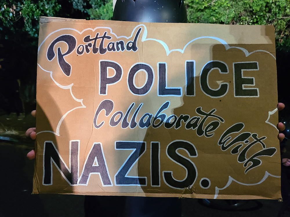 A handmade sign reflects on Portland Police Bureau's history of collaborating with the wrong side of history as well as the law.