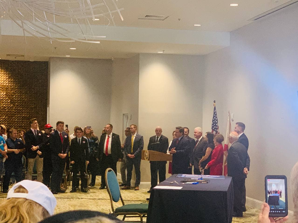 A bunch of people in suits standing around a hotel ballroom.