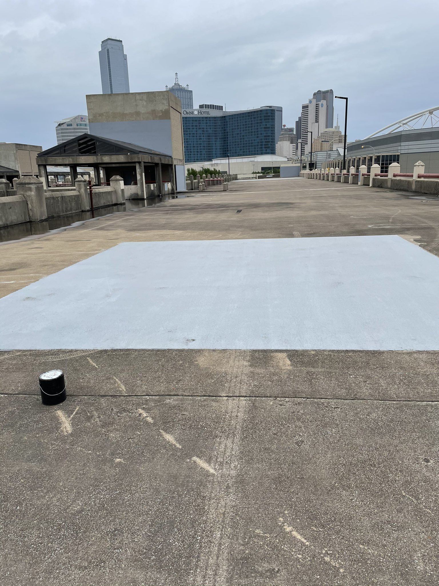 Photo of the same parking garage spot where Nazis had tagged, but it's covered in gray paint as if it was never there. A paint can sits next to the covered graffiti.