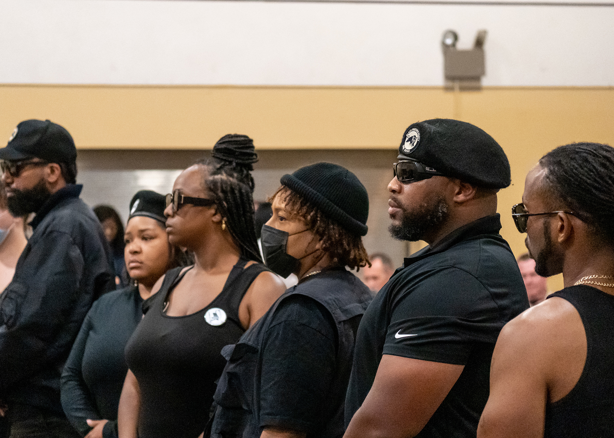 Members of the Black Panther Party of San Diego stand and look to the left of the frame, all of them in various articles of black clothing.