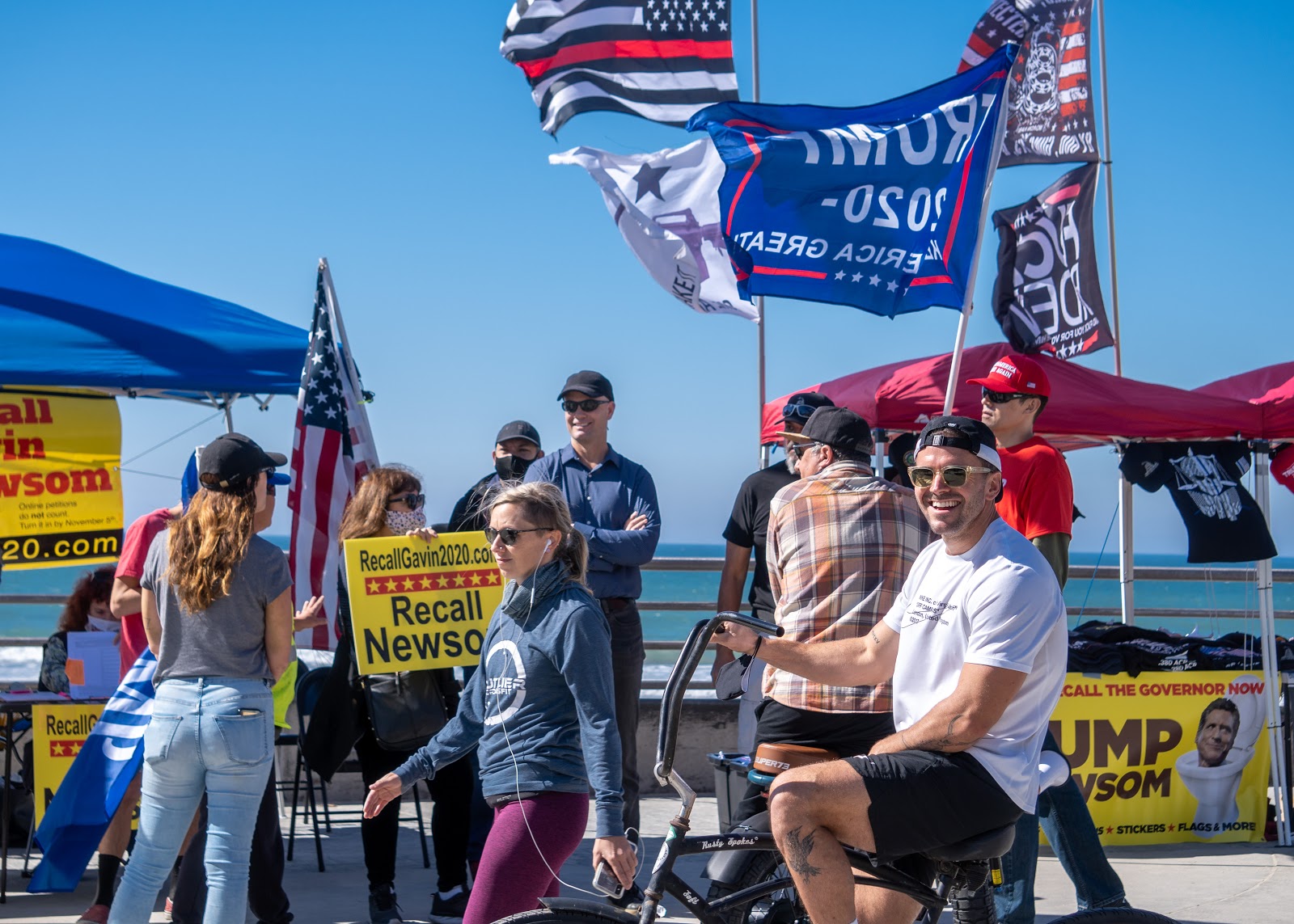 A man biking past the demonstration laughs at an exchange between onlookers and demonstrators