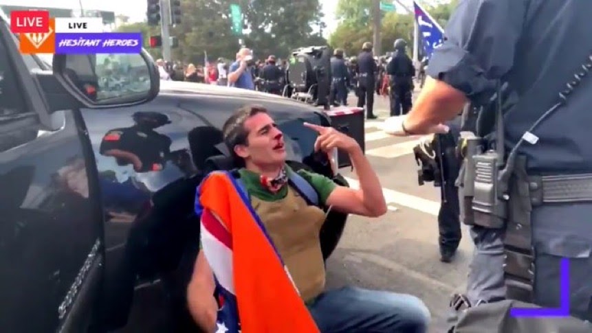 Edward Badalian crying with a broken nose while leaning on a cop car.