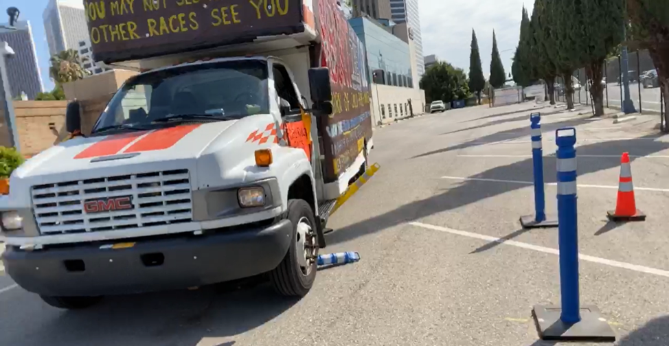 the GDL's banner-covered u haul truck parked in a parking lot across several spaces