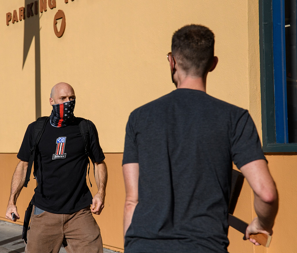 Neo-Nazi brandishes a knife in front of a counter-protestor with a sign.