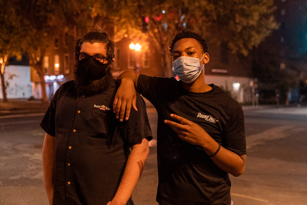 Nyjis Coleman (right) and a co-worker pose for a photo outside Round Table Pizza on Grand Avenue in Oakland, Calif., August 26, 2020. People protesting against the police shooting of Jacob Black in Kenosha, Wis. moved the restaurant’s dumpsters into the street to slow down police. Employees came out to retrieve the dumpsters after the protest had left the area.