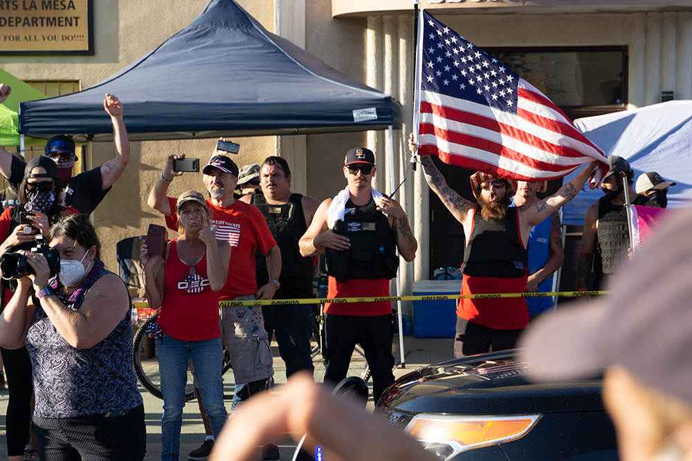 DEC protestors dressed in plate carriers with flags. Photo by Tom Mann.