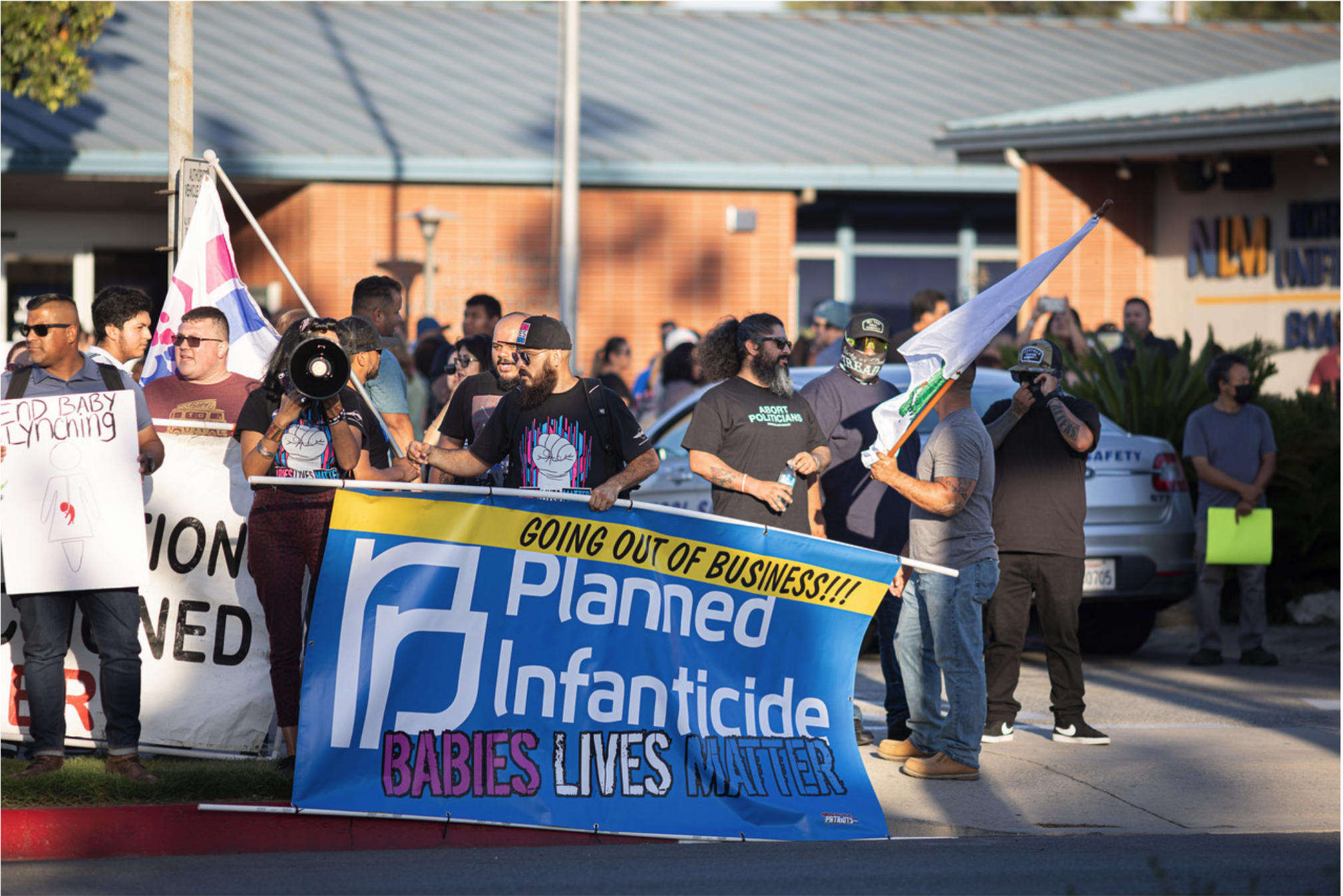 people gathering around a banner that says going out of business soon planned infanticide baby lives matter