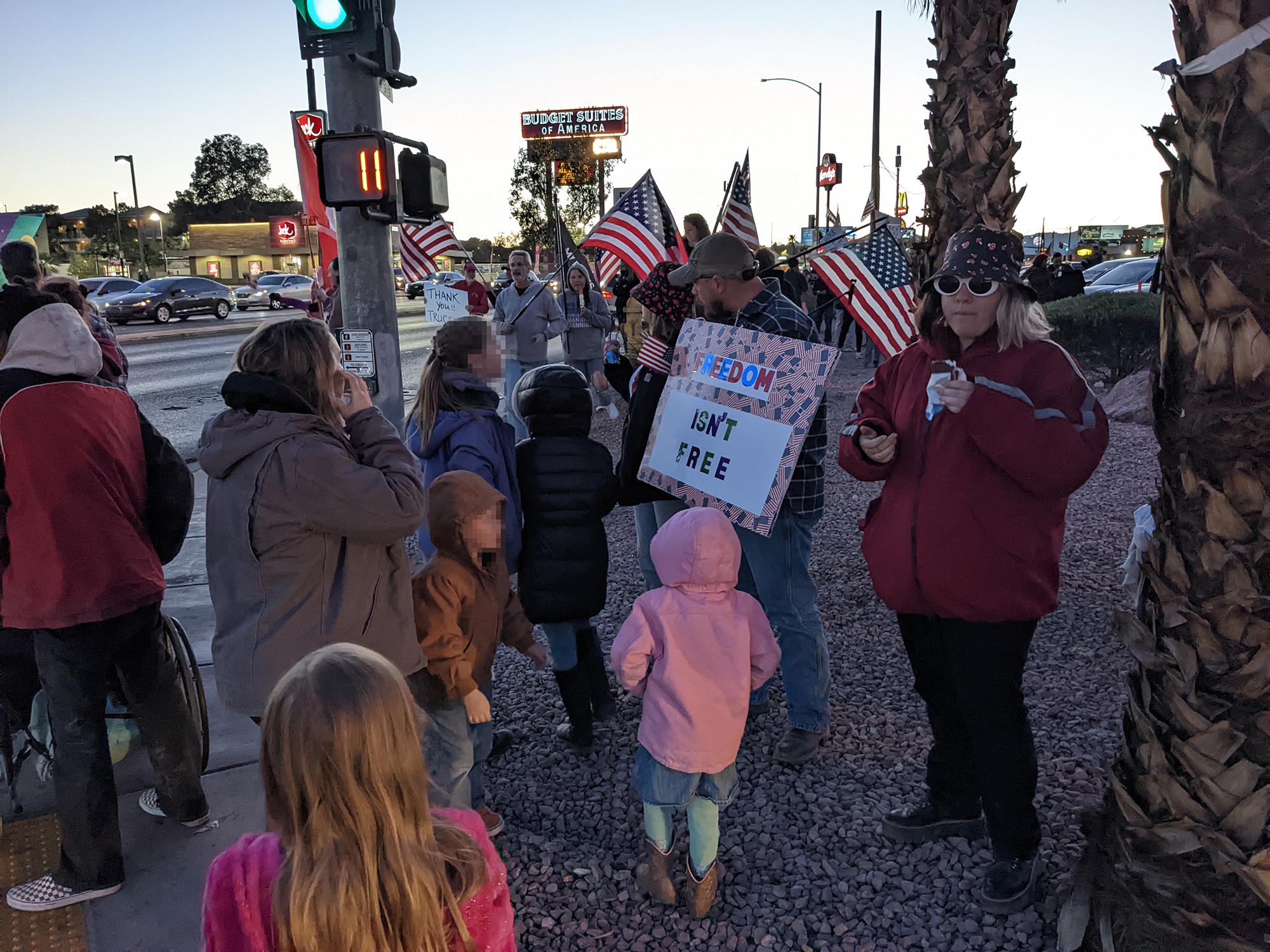 A bunch of kids in a crowd waving flags with adults we hope some of at least are their parents